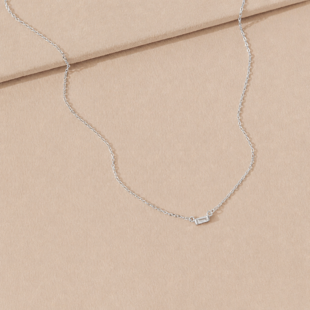 Silver necklace on a beige fabric background